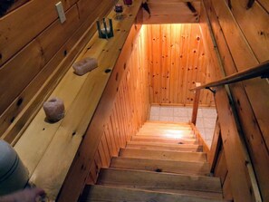Stairs lead to an upper level with a handrail and wooden walls and floor.