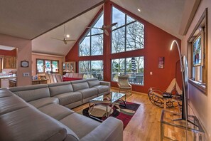 A spacious living room with a large sectional sofa, a glass coffee table, and a high ceiling with a fan. - Lake Cumberland Home w/ Deck + Water Access! (Monticello)