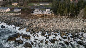 Une propriété située au bord de la rivière, avec une maison entourée d’une côte rocheuse et d’une zone boisée.