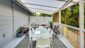 Ein überdachter Patio-Bereich mit Tisch, Stühlen, einer Couch und einem Blumentopf.