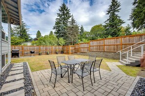 An outdoor patio with a table and chairs, a barbecue grill, and a wooden fence. - Redmond Retreat w/ Fenced Yard & EV Charger (Redmond)