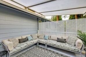 Ett takförsett utomhusområde med sittplatser, en modulsoffa och en mönstrad matta.