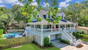 A two-story house with a covered porch, a swimming pool, and a well-maintained lawn.