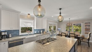 A modern kitchen with granite countertops, stainless steel appliances, and pendant lighting.