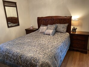 A neatly made bed with a patterned bedspread, a wooden headboard, a nightstand with a lamp, and a mirror on the wall. - Catskill Mountain House private 5 acre backyard,
Golf, Ski, Hike, Boating, Fish (Freehold)