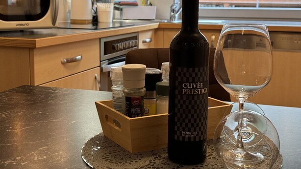Una cocina con microondas, horno y una botella de vino sobre la encimera.