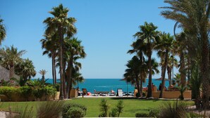 A resort with a pool area, palm trees, and a view of the ocean.