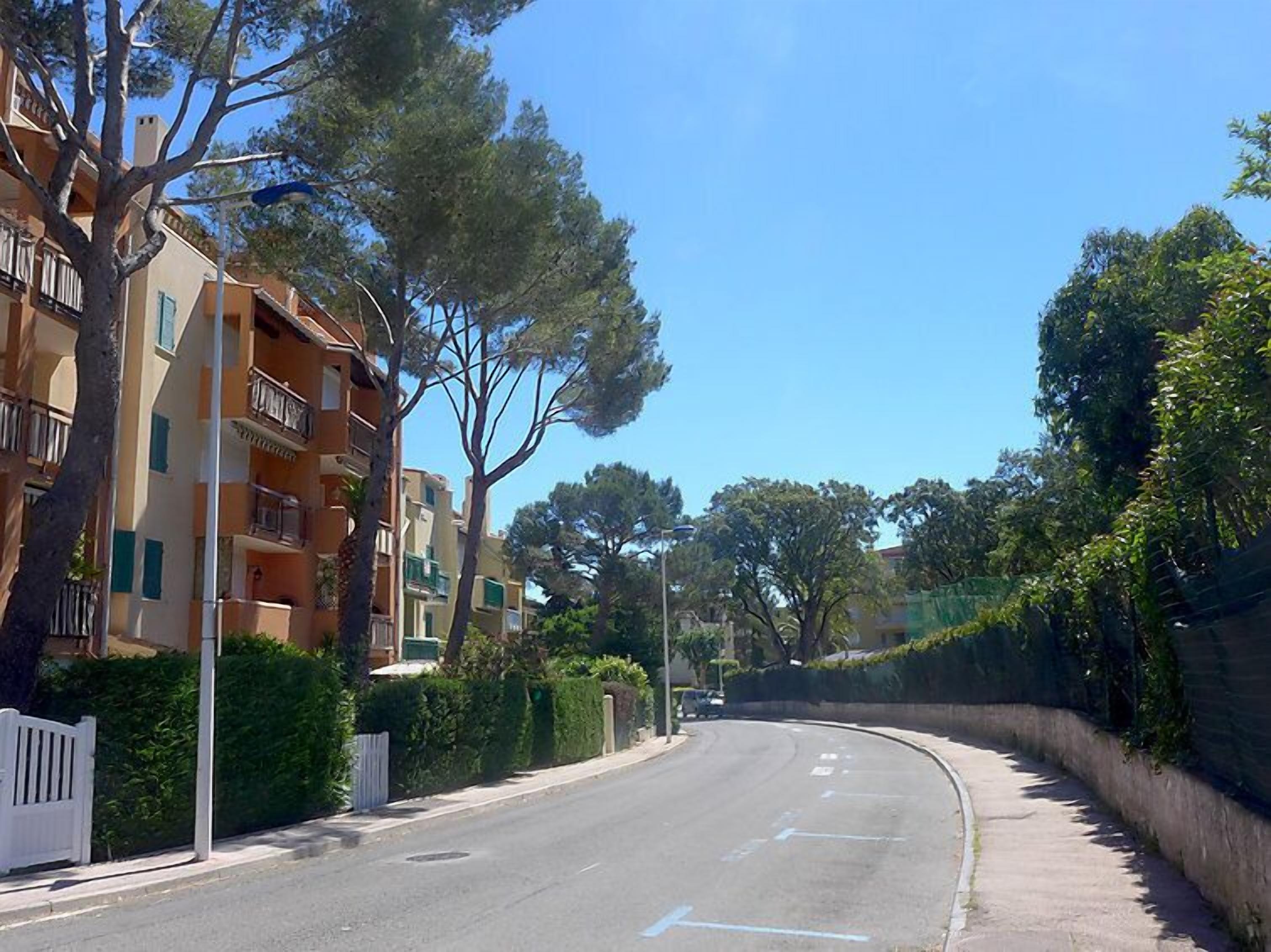 Une rue résidentielle bordée d’immeubles d’appartements, avec une route sinueuse et des arbres.