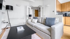 Ein modernes Wohnzimmer mit einem grauen Sofa, einem schwarzen Couchtisch und einem weißen Heizkörper.