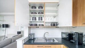 Eine moderne Küche mit weißen Schränken, einer Edelstahl-Spüle, einem Toaster, einer Kaffeemaschine und einer Mikrowelle.