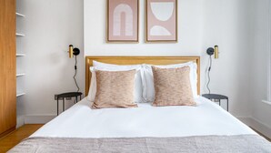 Ein ordentlich eingerichtetes Schlafzimmer mit einem großen Bett, zwei Nachttischen und einem Kleiderschrank.