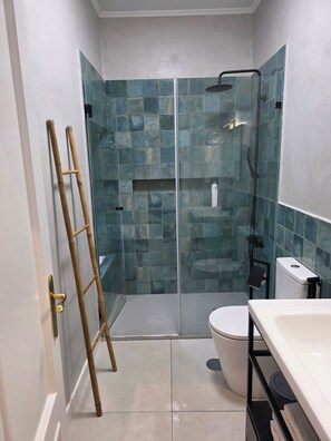 Une salle de bain avec une douche à parois de verre, des toilettes et un lavabo.