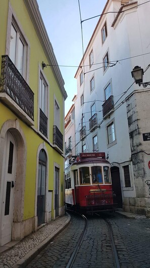 Une rue étroite, avec un tramway, des bâtiments aux couleurs vives et une chaussée pavée.