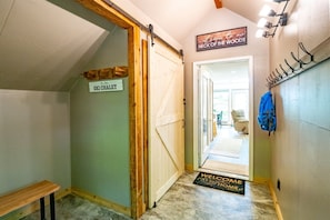 Ein Flur mit einer Holztür mit der Aufschrift "Ski Chalet", einer Fußmatte und einem Schild, auf dem "Willkommen in unserem Zuhause" steht.