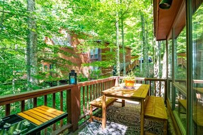A wooden deck with a table and chairs, surrounded by trees. - Trail Magic - 57 Mountain Laurel Lane (Davis)