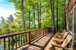A wooden deck with outdoor furniture, surrounded by tall trees.