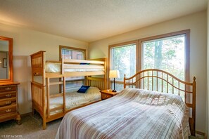 A bedroom with bunk beds, a bedside table with a lamp, a dresser, and a window with blinds. - Trail Magic - 57 Mountain Laurel Lane (Davis)