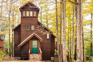 A wooden cabin with a green door, set in a forest with autumn foliage. - Trail Magic - 57 Mountain Laurel Lane (Davis)