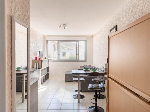 A modern kitchen with a dining area, a large window, and a view of the outside.