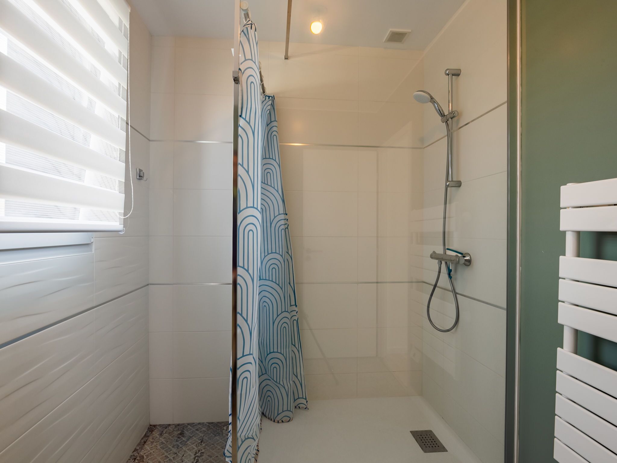 Un espace douche doté d’une porte en verre, d’un pommeau de douche et d’un rideau.