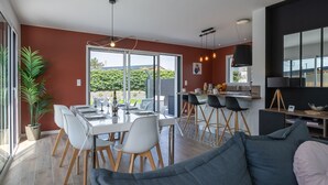 Ett modernt kök med en stor köksö, en matplats med ett glasbord och en mysig sittgrupp med en soffa.