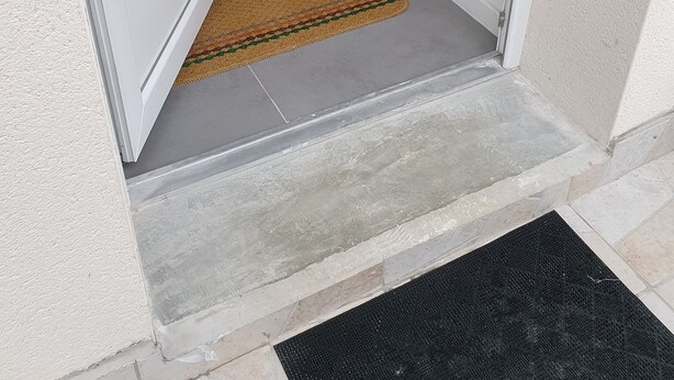 A doorway with a doormat and a black mat on the floor.
