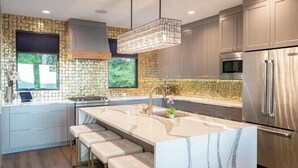 Una cocina moderna con una isla grande, electrodomésticos de acero inoxidable y un salpicadero de piedra.