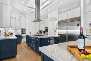 Una cocina moderna con armarios blancos, electrodomésticos de acero inoxidable y encimera de mármol.