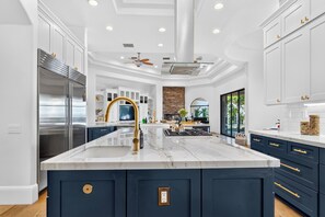 A modern kitchen with a central island, built-in appliances, and a stone accent wall.