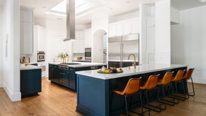 Une cuisine moderne dotée d’un îlot central, d’appareils électroménagers en acier inoxydable et d’un coin bar.