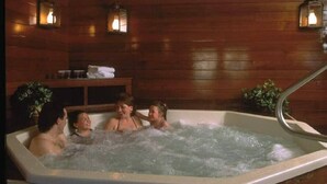Een jacuzzi met vier personen, houten wanden en wandlampen.