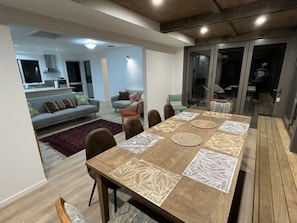 Un comedor con una mesa de madera, sillas y manteles individuales estampados.