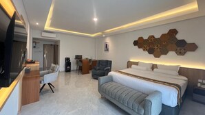 A modern hotel room with a large bed, a sofa, a desk, and a TV. - Front One The Andia Boyolali (Boyolali)