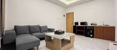 A modern living room with a grey sectional sofa, a glass-top coffee table, and a wooden cabinet.