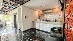A reception area with a marble floor, a receptionist desk, a clock, and a sign that reads 'FRONT ONE THE ANDIA'. - Front One The Andia Boyolali (Boyolali)