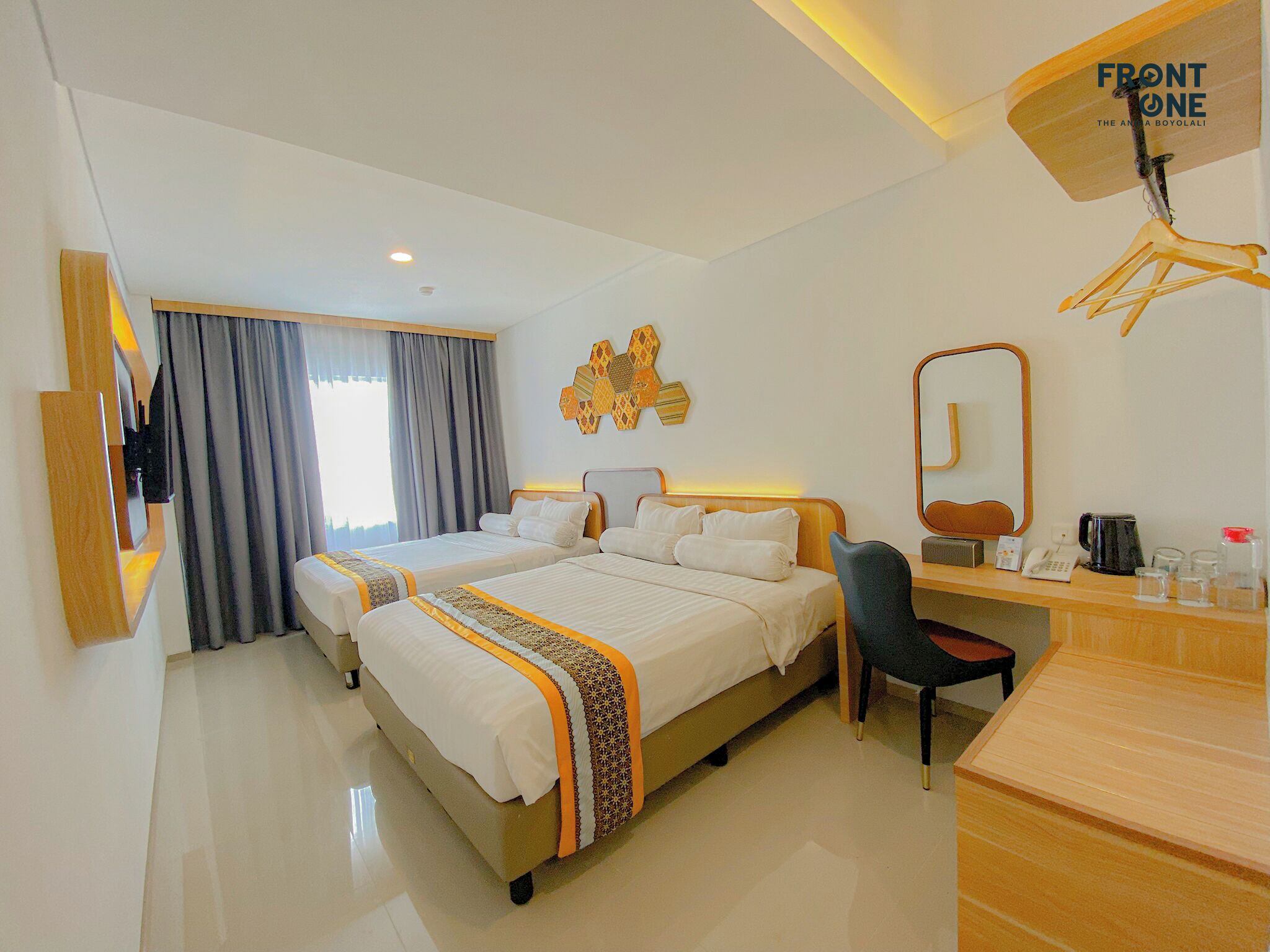 Habitación de hotel con cama, escritorio, silla, espejo y televisor.
