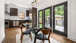 A modern kitchen with dark cabinetry, stainless steel appliances, and a glass dining table with chairs. - " Top Notch House In Perfect Location" (Atlanta)