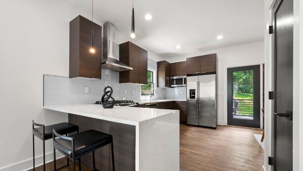 A modern kitchen with a central island, stainless steel appliances, and dark wooden cabinets. - " Top Notch House In Perfect Location" (Atlanta)