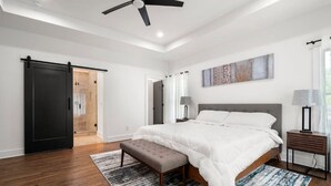 A bedroom with a bed, a bench, a nightstand, a lamp, a ceiling fan, and a sliding door. - " Top Notch House In Perfect Location" (Atlanta)