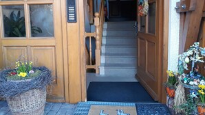 Une porte d’entrée en bois dotée d’un clavier pour ouvrir à l’aide d’un code, un escalier menant à l’étage supérieur et un paillasson orné d’un motif d’oiseau.