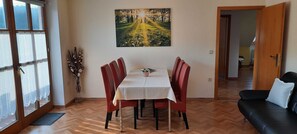 Ein Essbereich mit Tisch, Stühlen, einem Gemälde, einer Vase und einem Sofa.