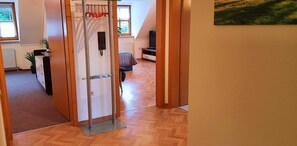 Une pièce avec un plancher en bois, un lit recouvert d’une couverture à rayures, une télévision et une plante.