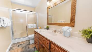 Un baño con ducha, inodoro, lavamanos y armarios de madera.
