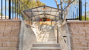 A set of stone steps leading up to a covered area with a metal railing and a hanging light fixture.