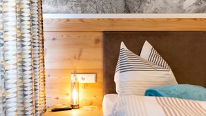 Ett hotellrum med en sänggavel i trä, en sänglampa, en fjärrkontroll och randigt sänglinne.