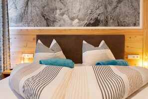 A hotel room with a large bed, striped bedding, a wooden headboard, and a wall-mounted artwork.