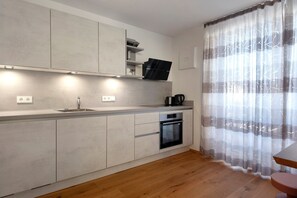 A modern kitchen with built-in appliances, a countertop, and a wooden floor.