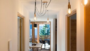 A hallway with a dining area, wooden flooring, and a view of the outdoors. - Holiday Apartment "Noreia Granda" with Mountain View, Pool, Wi-Fi, Terrace & Balcony (St.Ulrich)