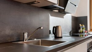 A modern kitchen with a stainless steel sink, a kettle, and a coffee maker on the counter. - Holiday Apartment "Noreia Granda" with Mountain View, Pool, Wi-Fi, Terrace & Balcony (St.Ulrich)