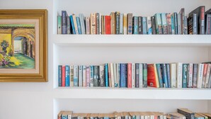 Une bibliothèque remplie de livres, un tableau encadré et un mur blanc.